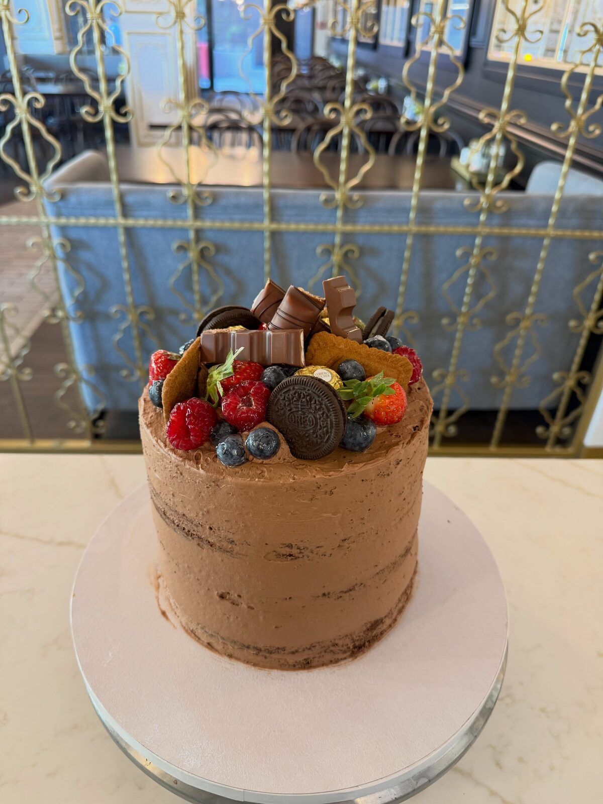Schokoladentorte mit Beeren und Keksen vor dem goldenen Gitter im Café
