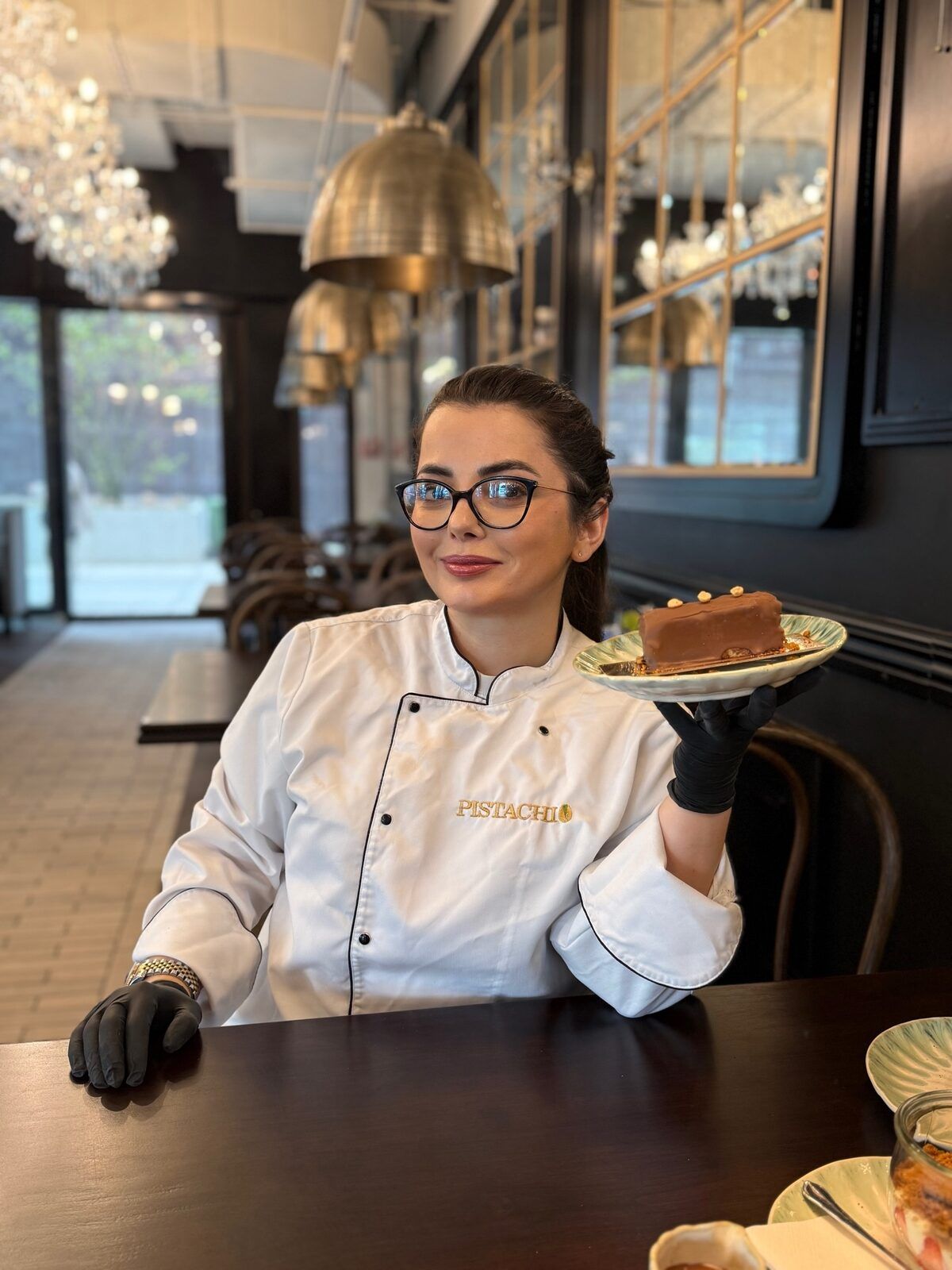 Konditorin von Pistachio mit einem frisch glasierten Dessert im Café, Kronleuchter und Messinglampen im Hintergrund