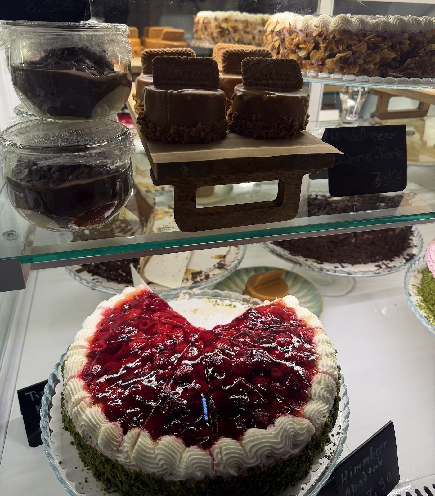 Torten in der Vitrine: Heidelbeer-Sahne-Torte, Himbeer-Obsttorte und Lotus-Törtchen