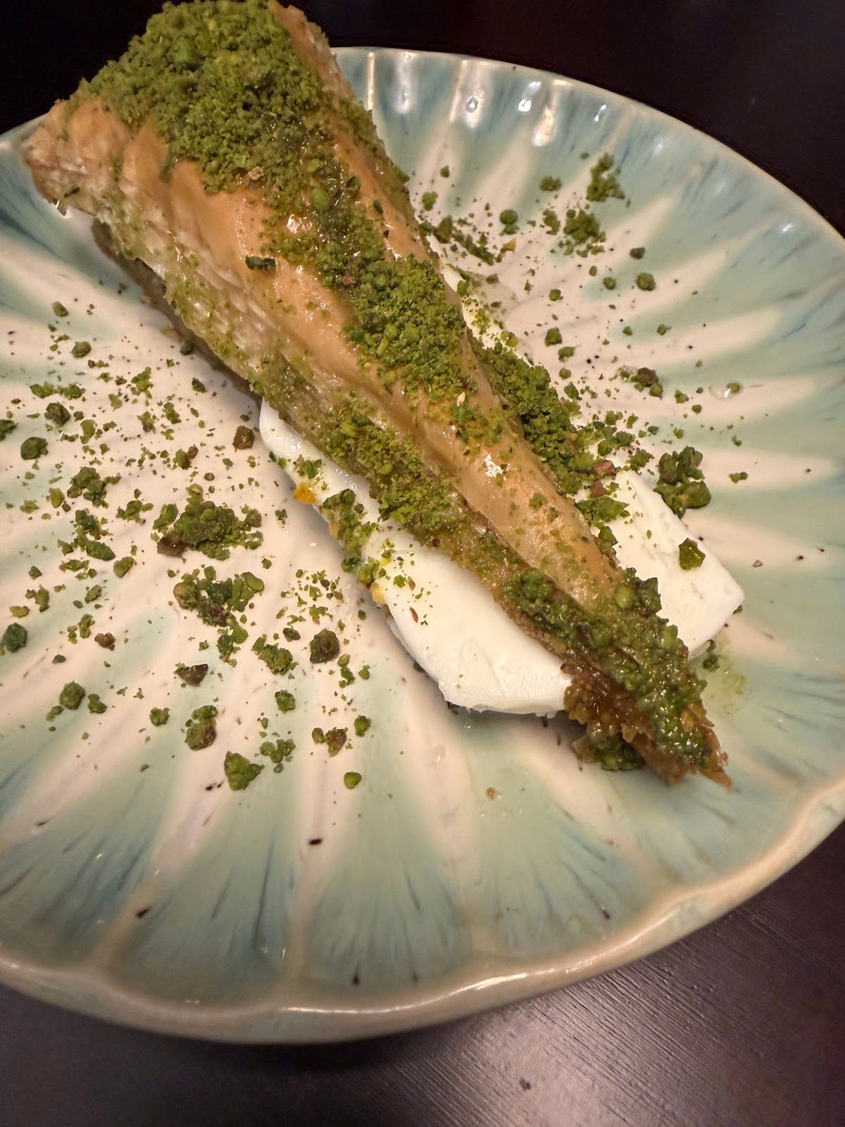 Pistazien-Baklava-Stueck mit Pistazienstreu auf tuerkisem Teller